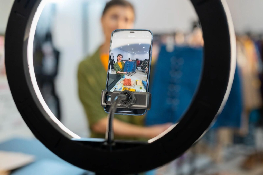 Smartphone in holder shows clear shot of woman wearing shirt while she remains blurred in the background